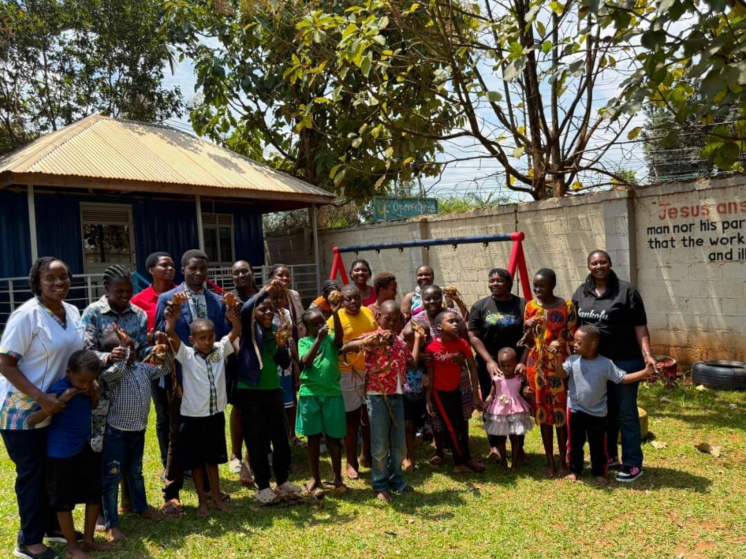 Learners, teachers and Sankofa volunteers standing together in the school compound, holding up the pieces they made from banana fibre.