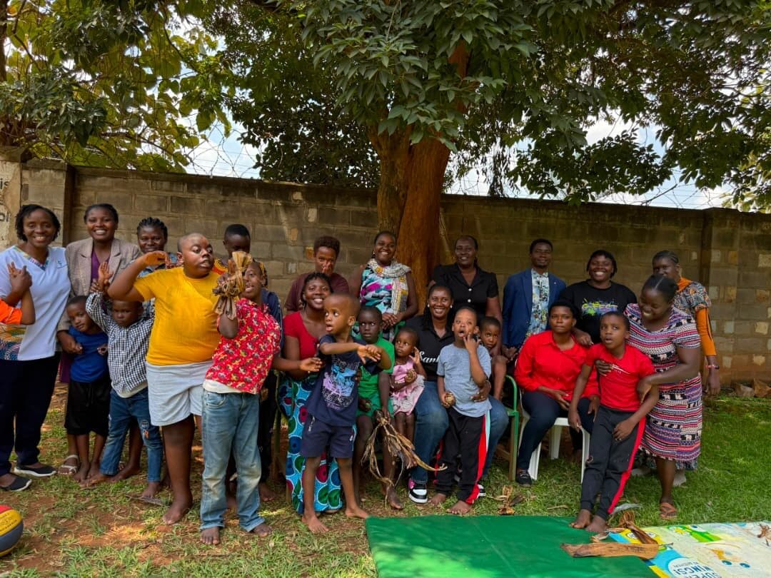 The full group of learners, teachers and volunteers gathered together under a large tree in the compound.